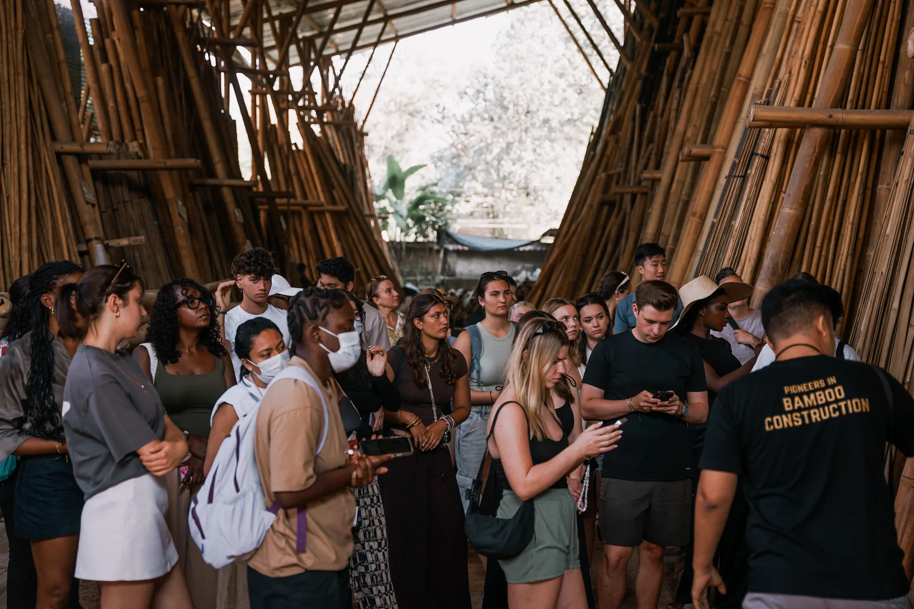 Students among tall racks of bamboo poles at the bamboo factory