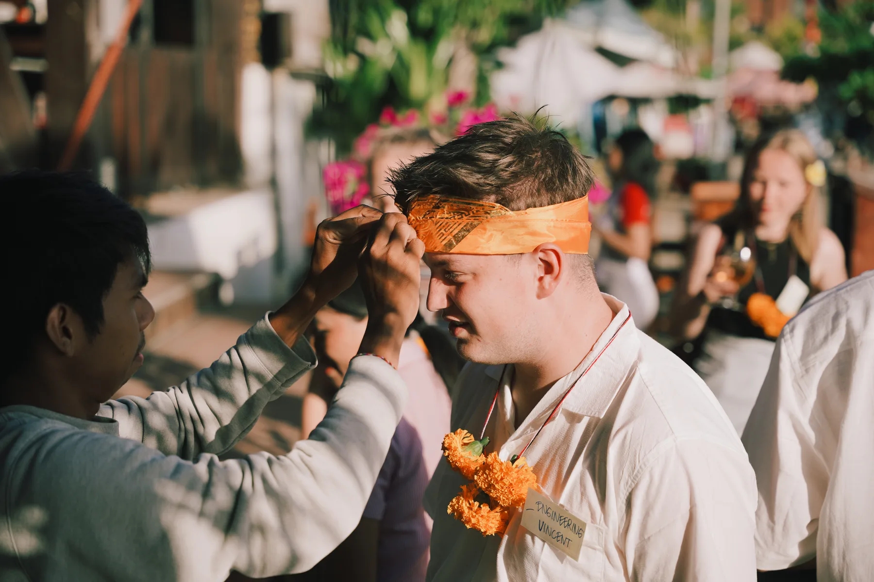 A staff member tying an udeng, the traditional head cloth, on a student named Vincent
