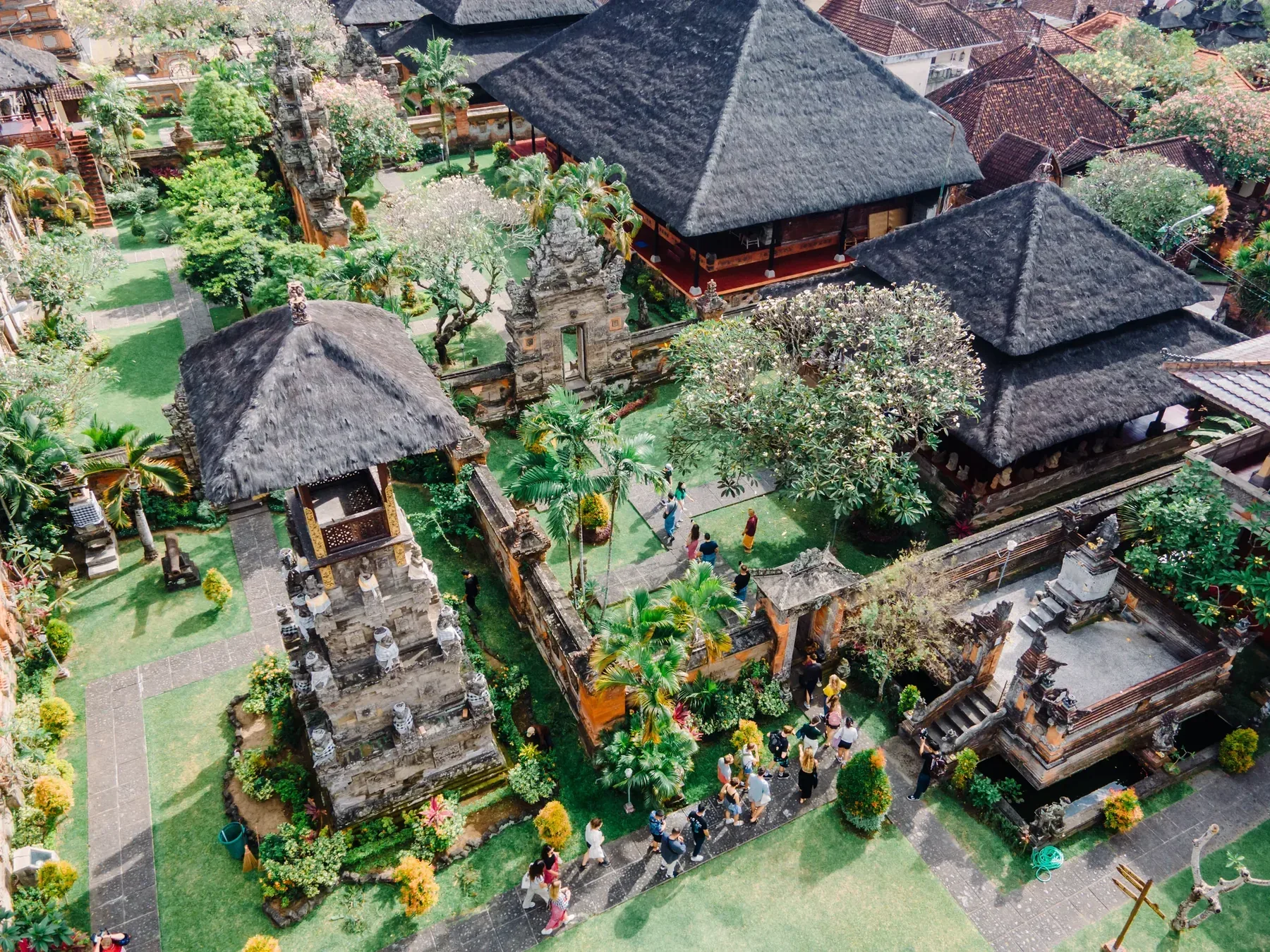 Aerial view of traditional Balinese buildings with thatched roofs, courtyards and gardens